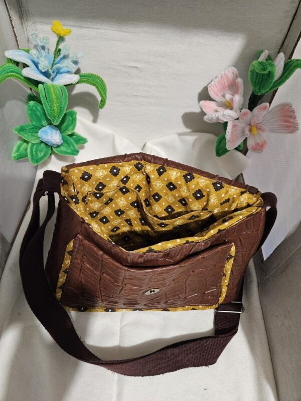 Sac à bandoulière en simili cuir marron et tissu à motif avec une poche devant et une poche a l'intérieur et une anse réglable.